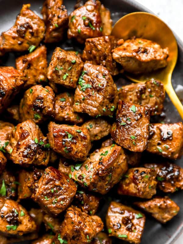 Garlic butter steak bites with browned edges and fresh parsley in a bowl.