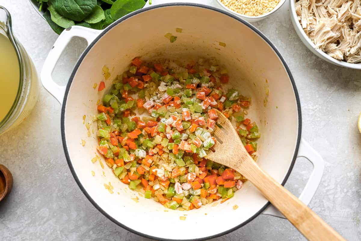Flour added to sautéed vegetables in a pot to thicken lemon chicken orzo soup base