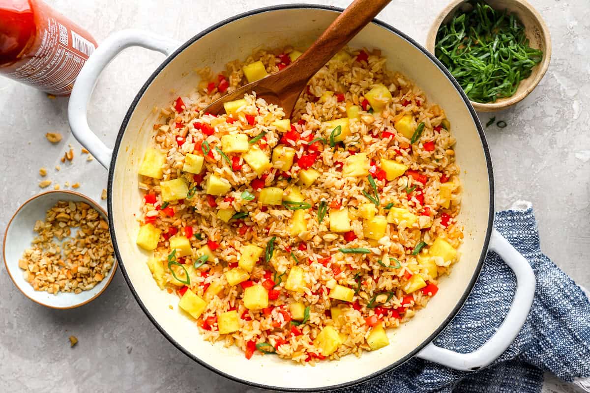 Fresh pineapple chunks added to fried rice in a skillet