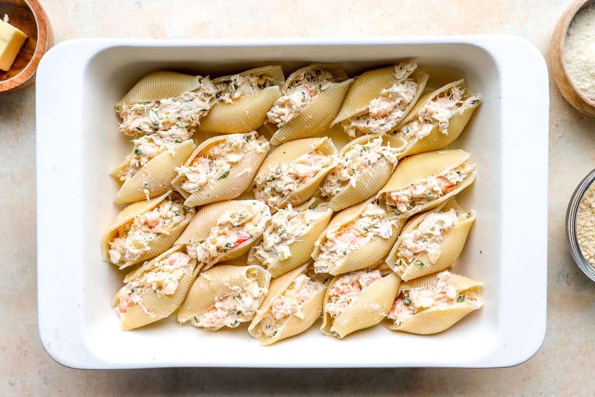 Jumbo pasta shells filled with creamy shrimp and crab mixture arranged in a baking dish.