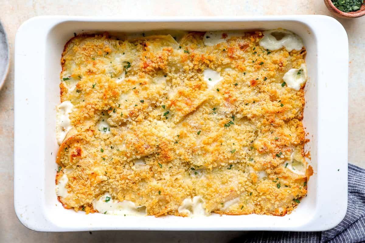 Baked seafood stuffed shells with golden breadcrumb topping and creamy sauce in a white casserole dish.