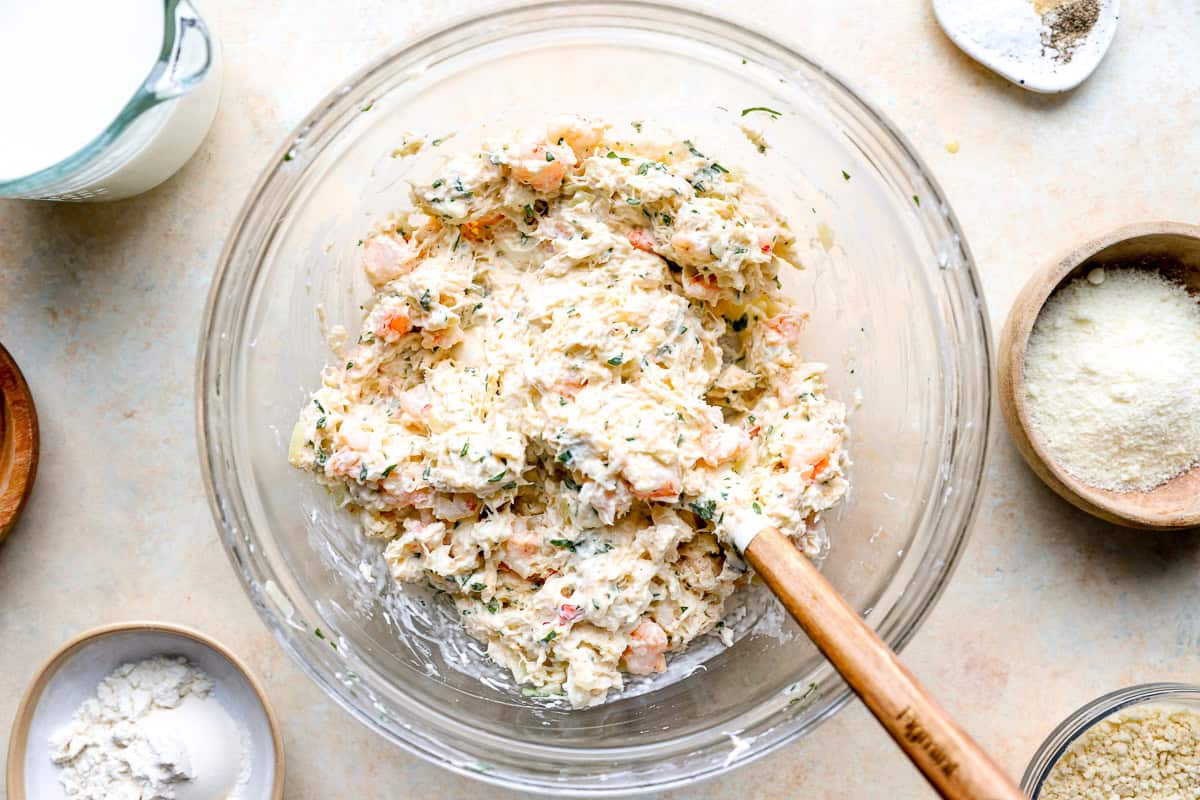 Shrimp and crab seafood filling mixed with cream cheese, mayonnaise, and parsley in a glass bowl.