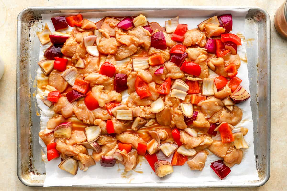 Chicken, peppers, and red onion spread on a sheet pan before baking