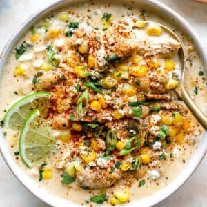 Street corn white chicken chili topped with cotija cheese, corn, cilantro, chili powder, and lime in a bowl