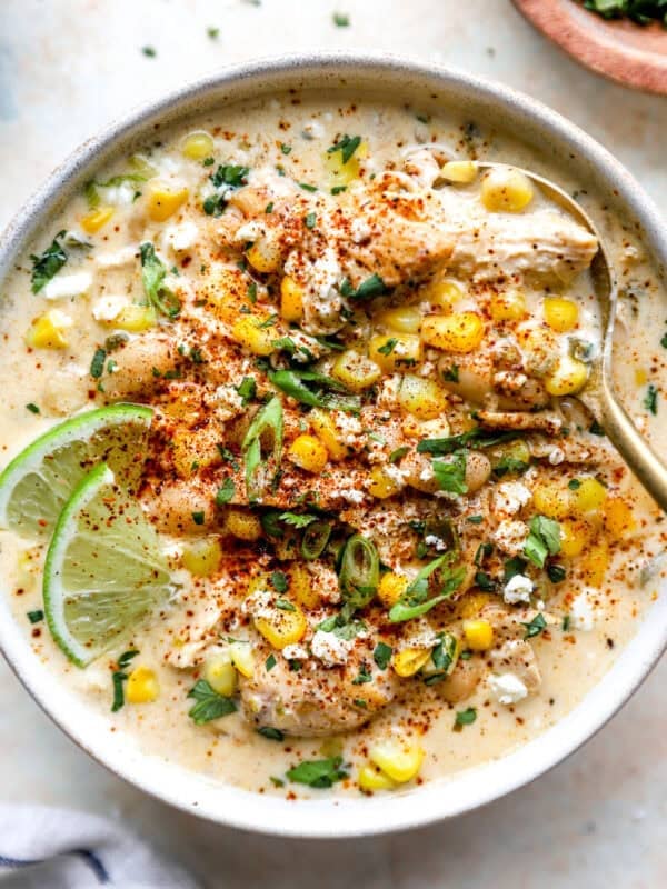 Street corn white chicken chili topped with cotija cheese, corn, cilantro, chili powder, and lime in a bowl