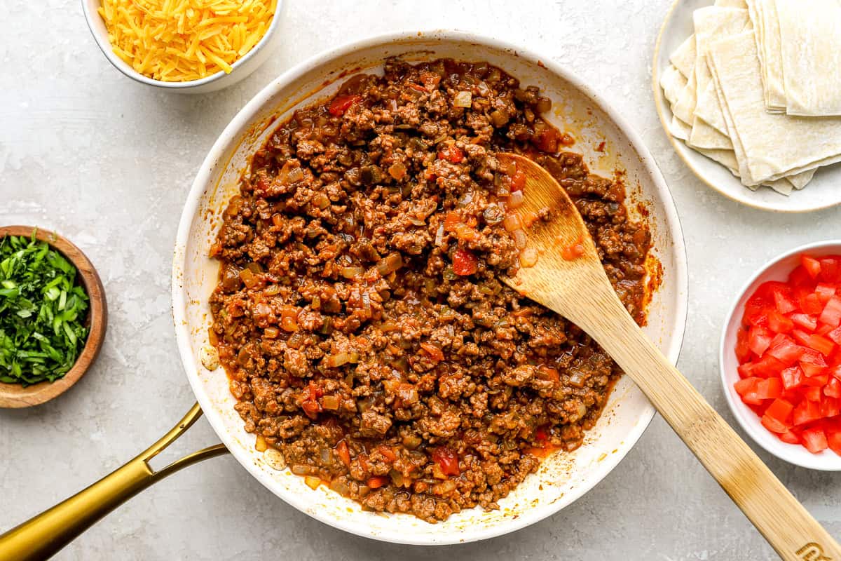 Cooked taco meat mixture in a skillet with diced peppers and onions