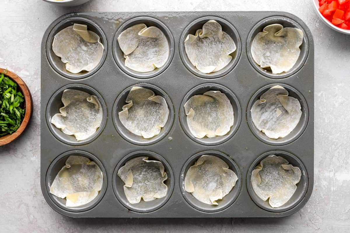 Wonton wrappers pressed into a muffin tin to form taco cup shells