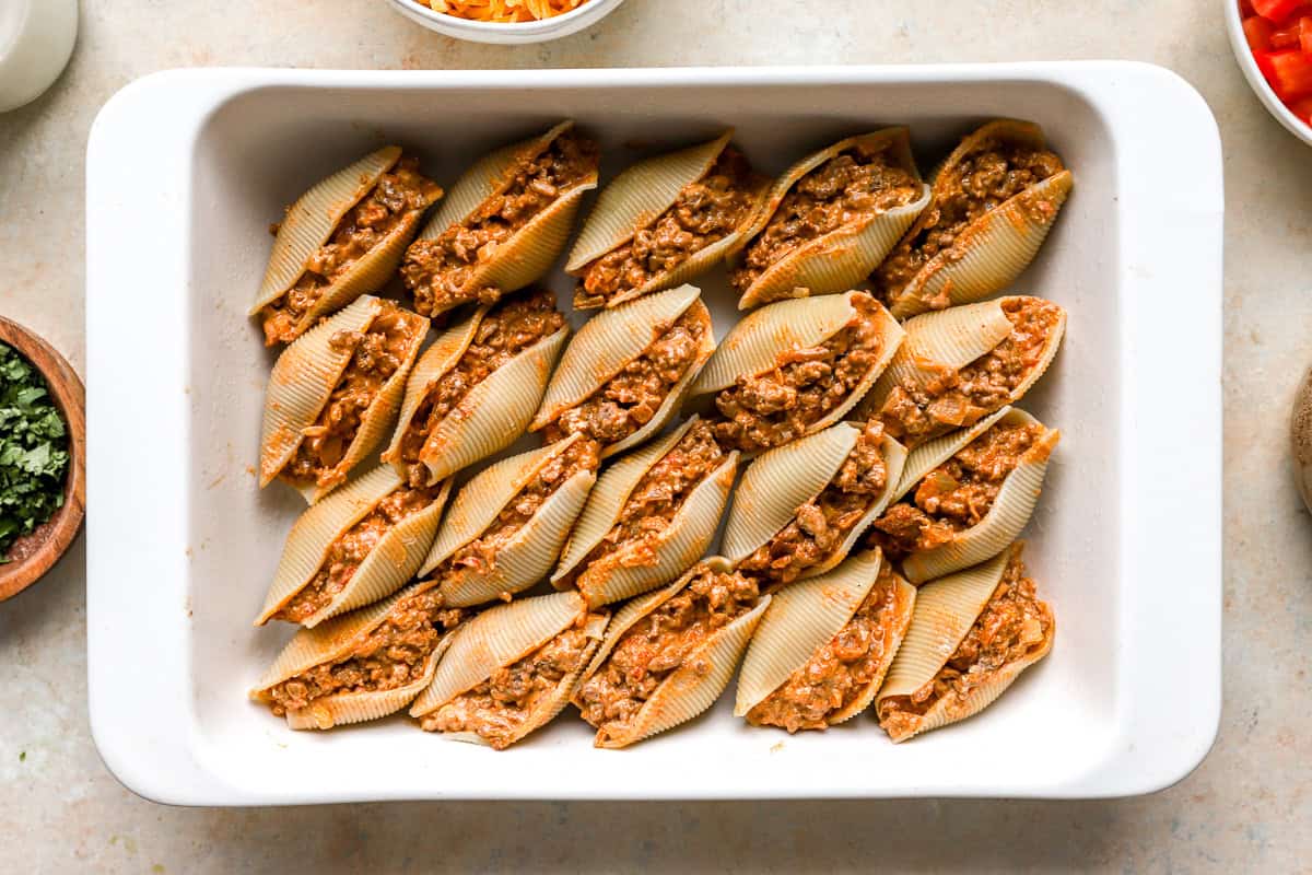 Cooked jumbo pasta shells drying on paper towels before stuffing.