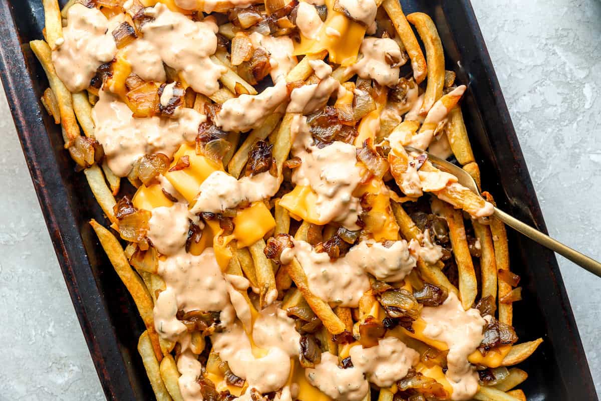 Overhead view of loaded animal style fries with melted cheese, onions, and sauce