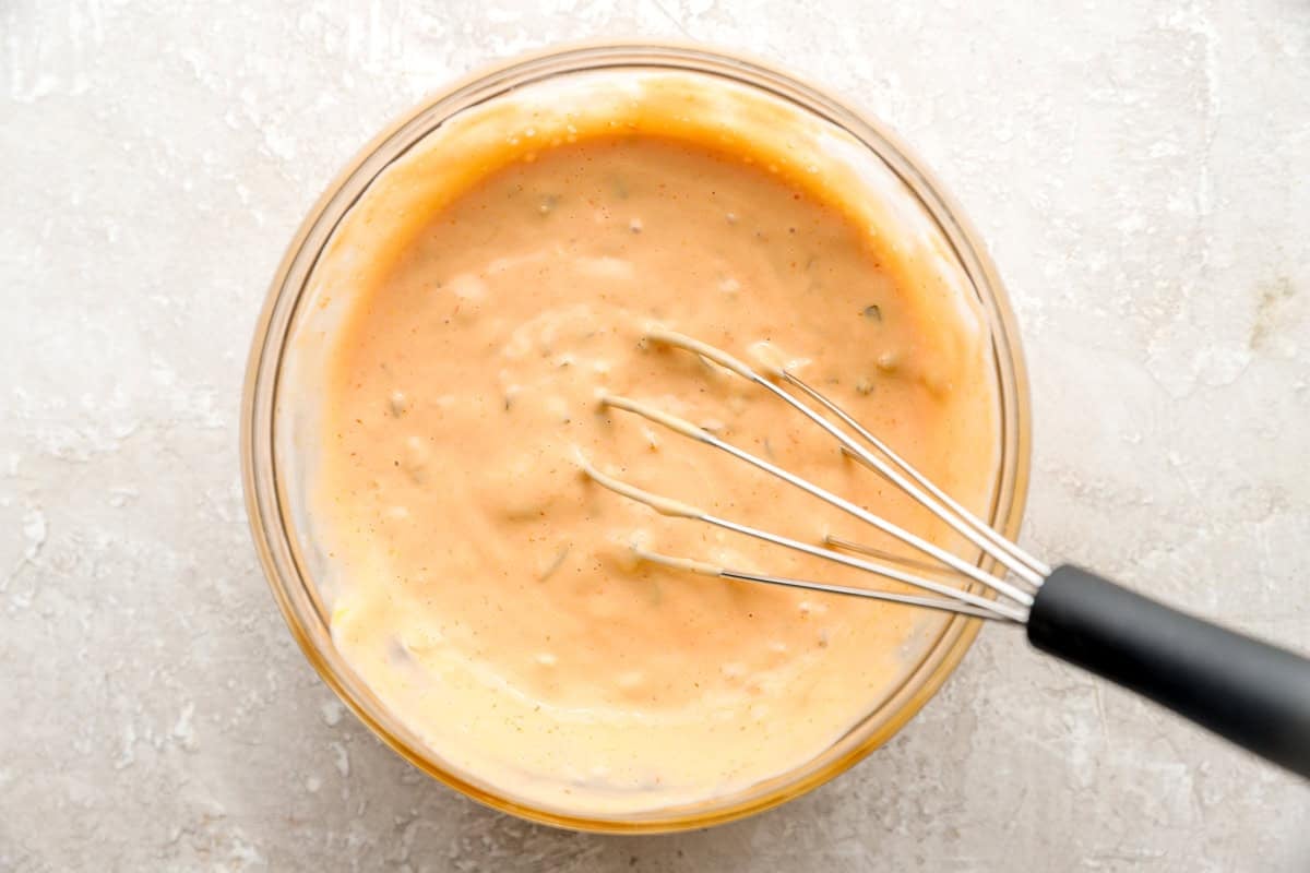 Creamy Thousand Island-style sauce being whisked in a glass bowl