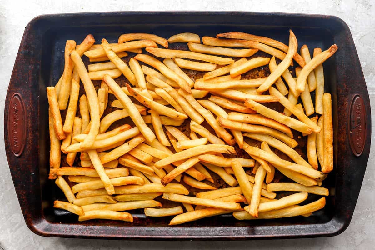 Crispy golden French fries spread evenly on a baking sheet