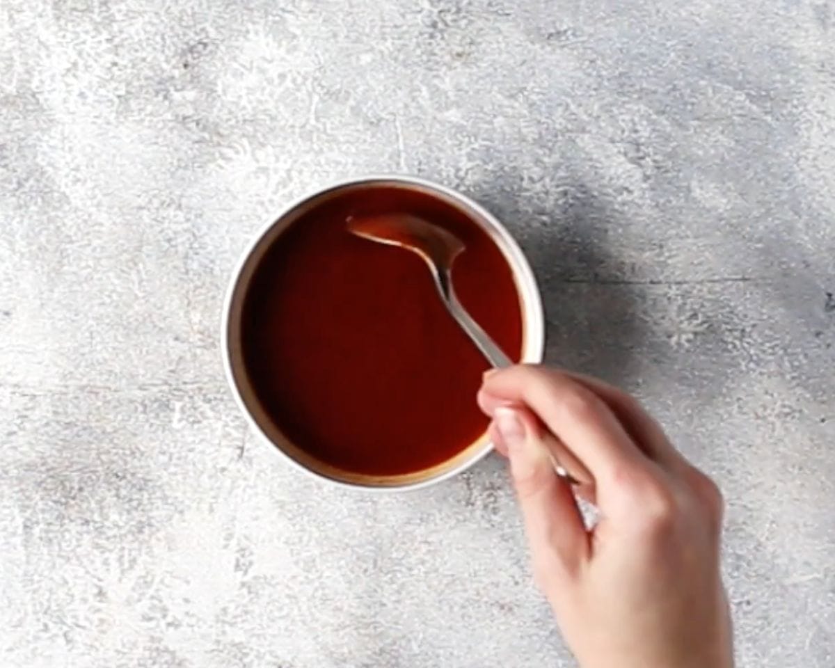 BBQ sauce being mixed in a small bowl with a spoon