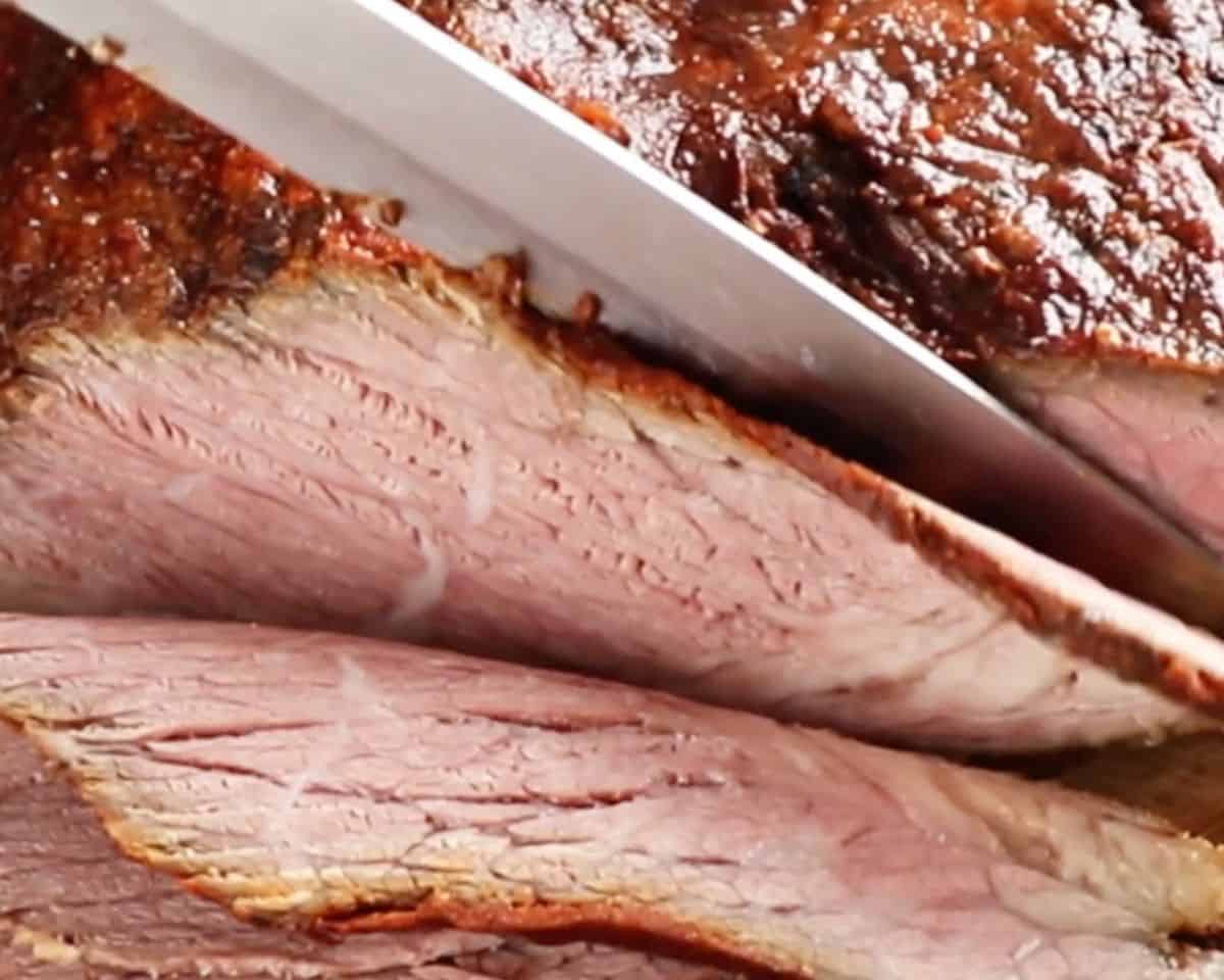 Close-up of cooked brisket being sliced into thick pieces