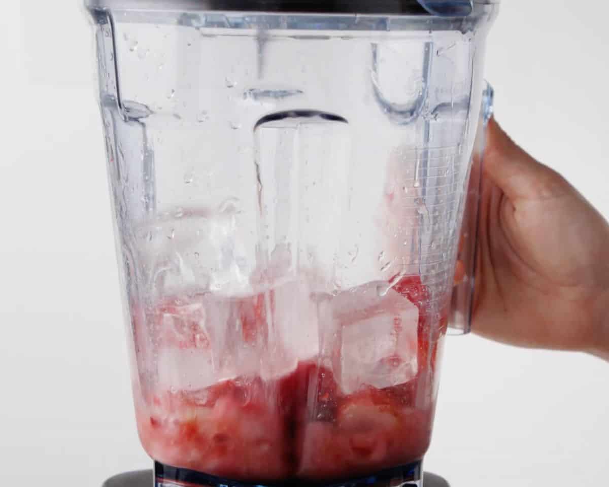 Frozen strawberries, tequila, lime juice, Cointreau, and ice added to a blender before mixing.