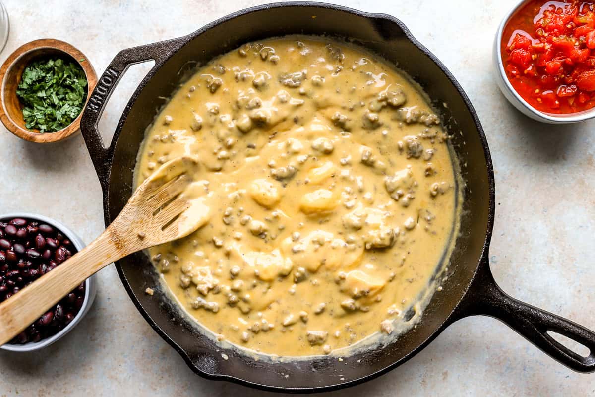 Melting Velveeta cheese with sausage in a skillet until smooth and creamy