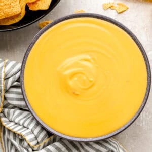 Smooth, creamy nacho cheese sauce in a bowl with tortilla chips on the side.