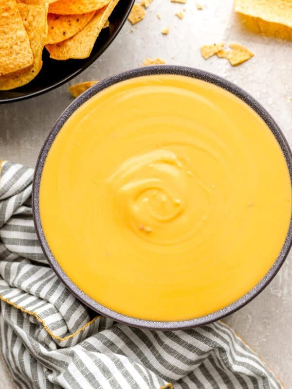 Smooth, creamy nacho cheese sauce in a bowl with tortilla chips on the side.