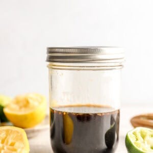 Ponzu sauce in a mason jar with fresh lemon and lime halves on a light surface