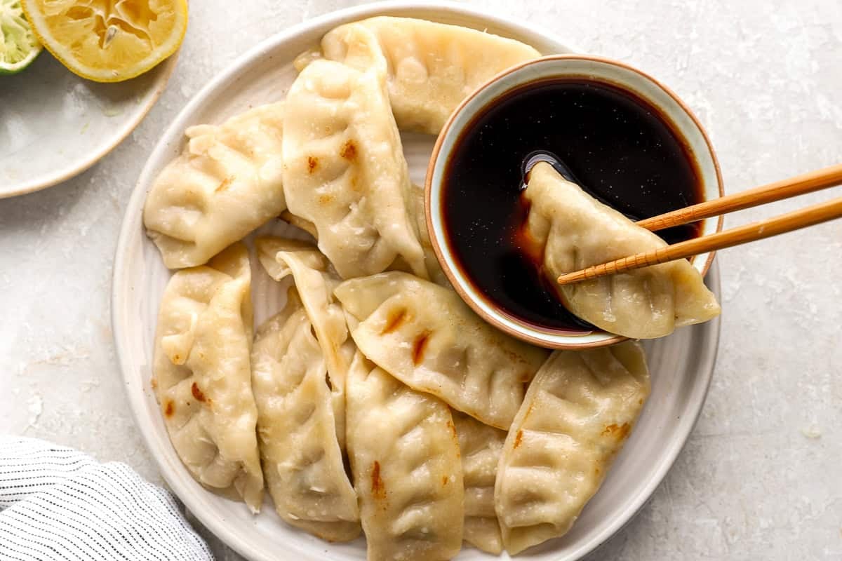 Plate of pan-fried dumplings served with ponzu dipping sauce and chopsticks
