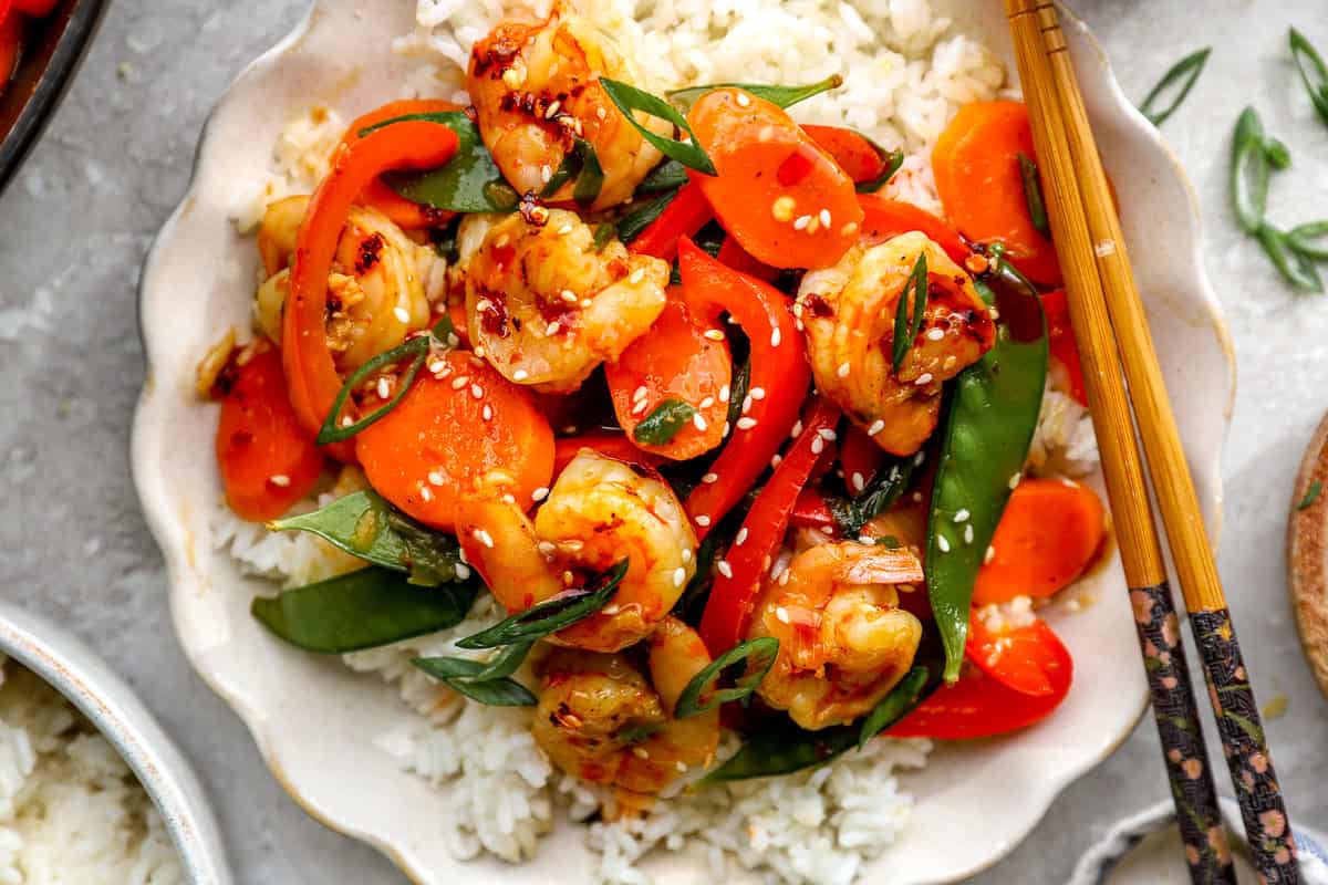 Close up of shrimp stir fry over rice topped with sesame seeds and green onions