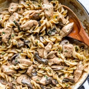 Creamy chicken stroganoff with egg noodles, mushrooms, and parsley in a large skillet