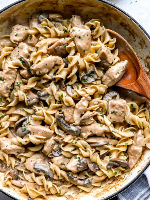 Creamy chicken stroganoff with egg noodles, mushrooms, and parsley in a large skillet