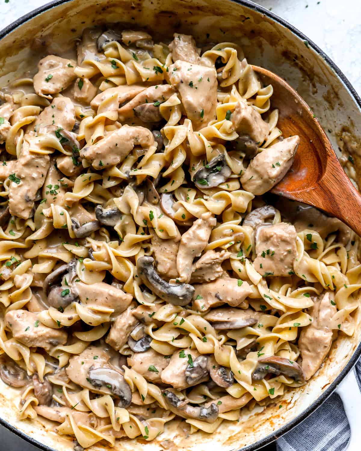 Creamy chicken stroganoff with egg noodles, mushrooms, and parsley in a large skillet