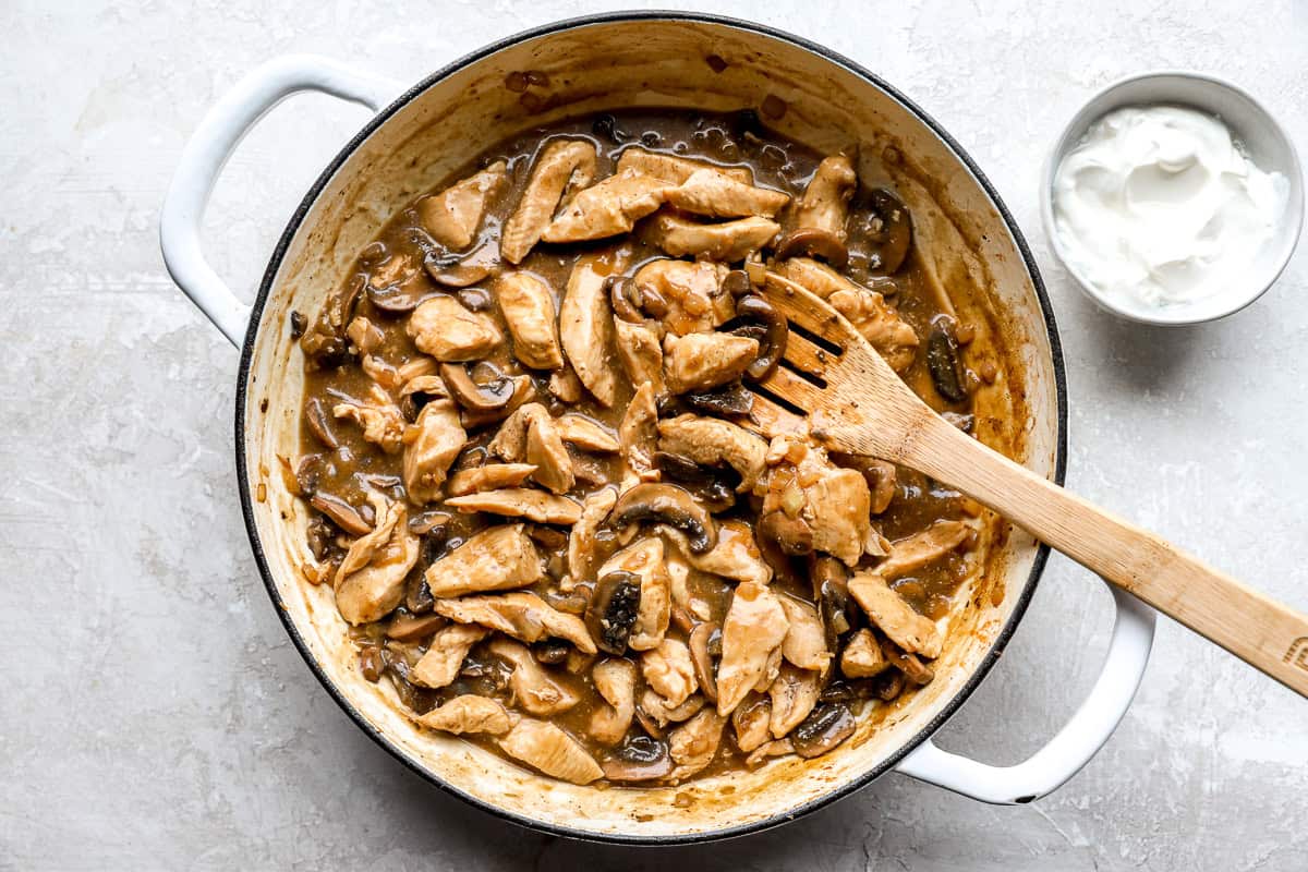 Chicken and mushrooms simmering in savory stroganoff sauce in a skillet