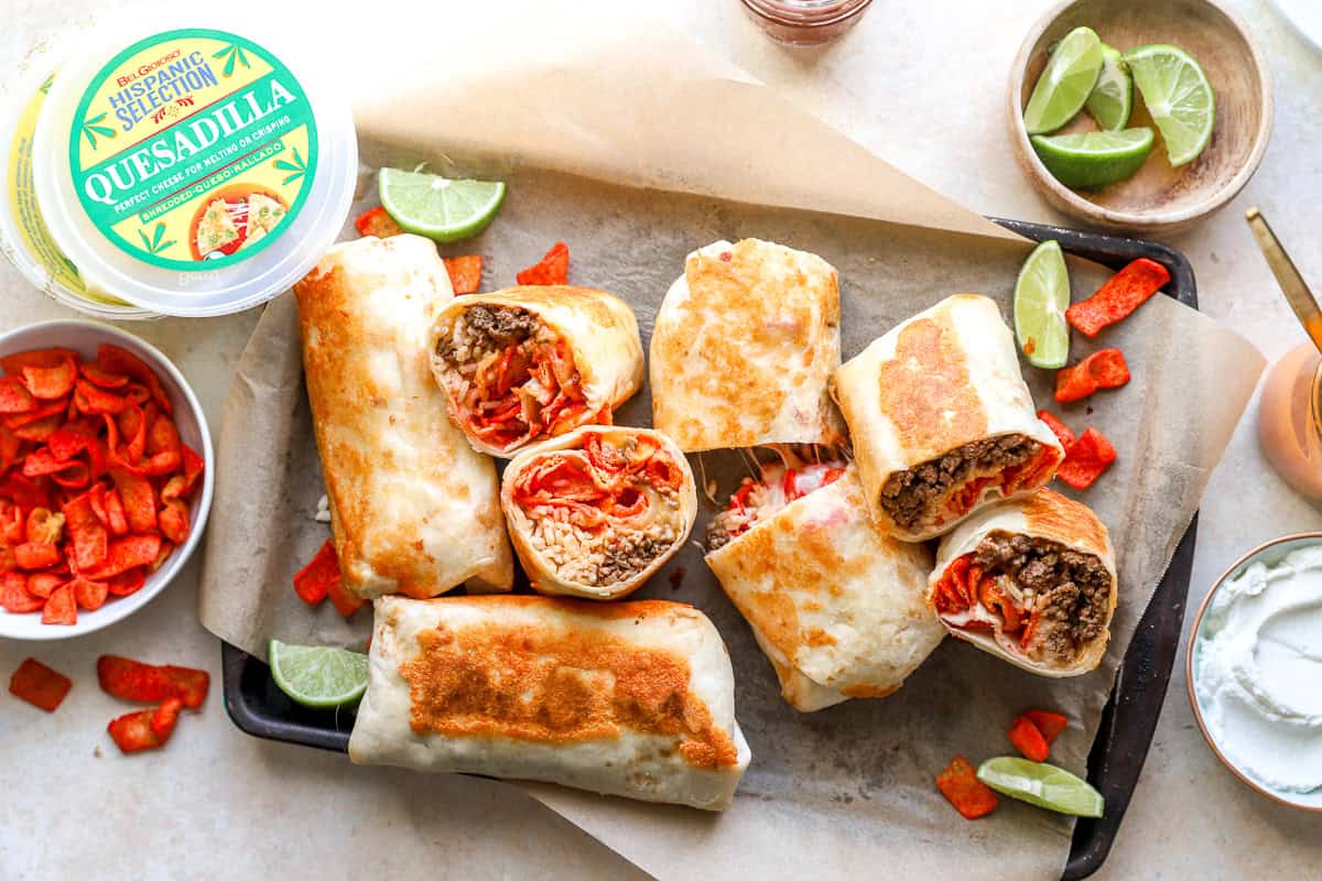 finished flamin' hot grilled cheese burrito on a baking sheet with garnishes on the side