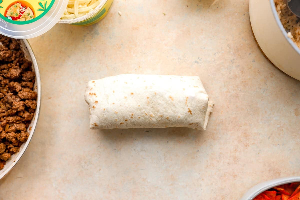 Fully rolled Flamin’ Hot grilled cheese burrito before crisping in the skillet.