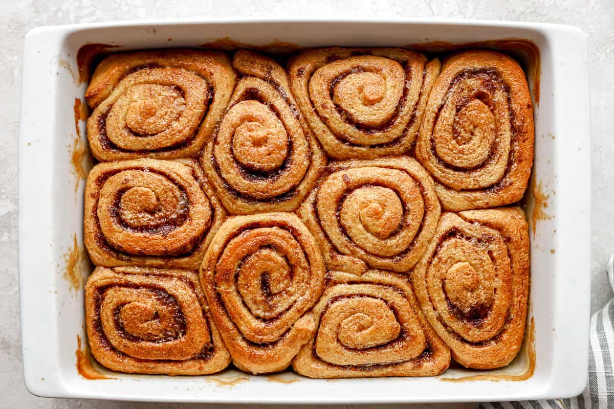 Baked heavy cream cinnamon rolls in a baking dish with golden brown tops and gooey cinnamon filling.