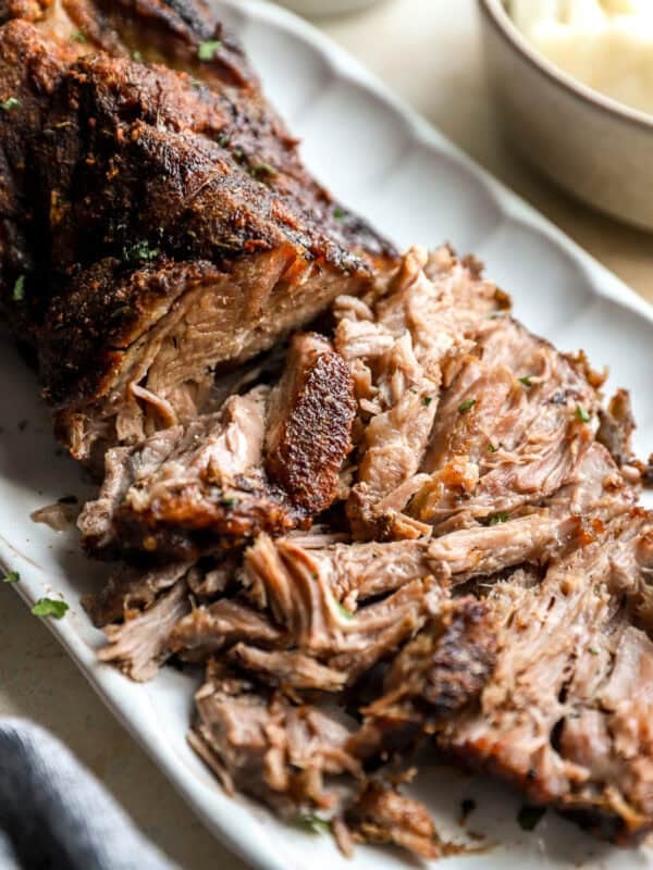 Shredded roasted pork shoulder with crispy browned edges served on a platter.