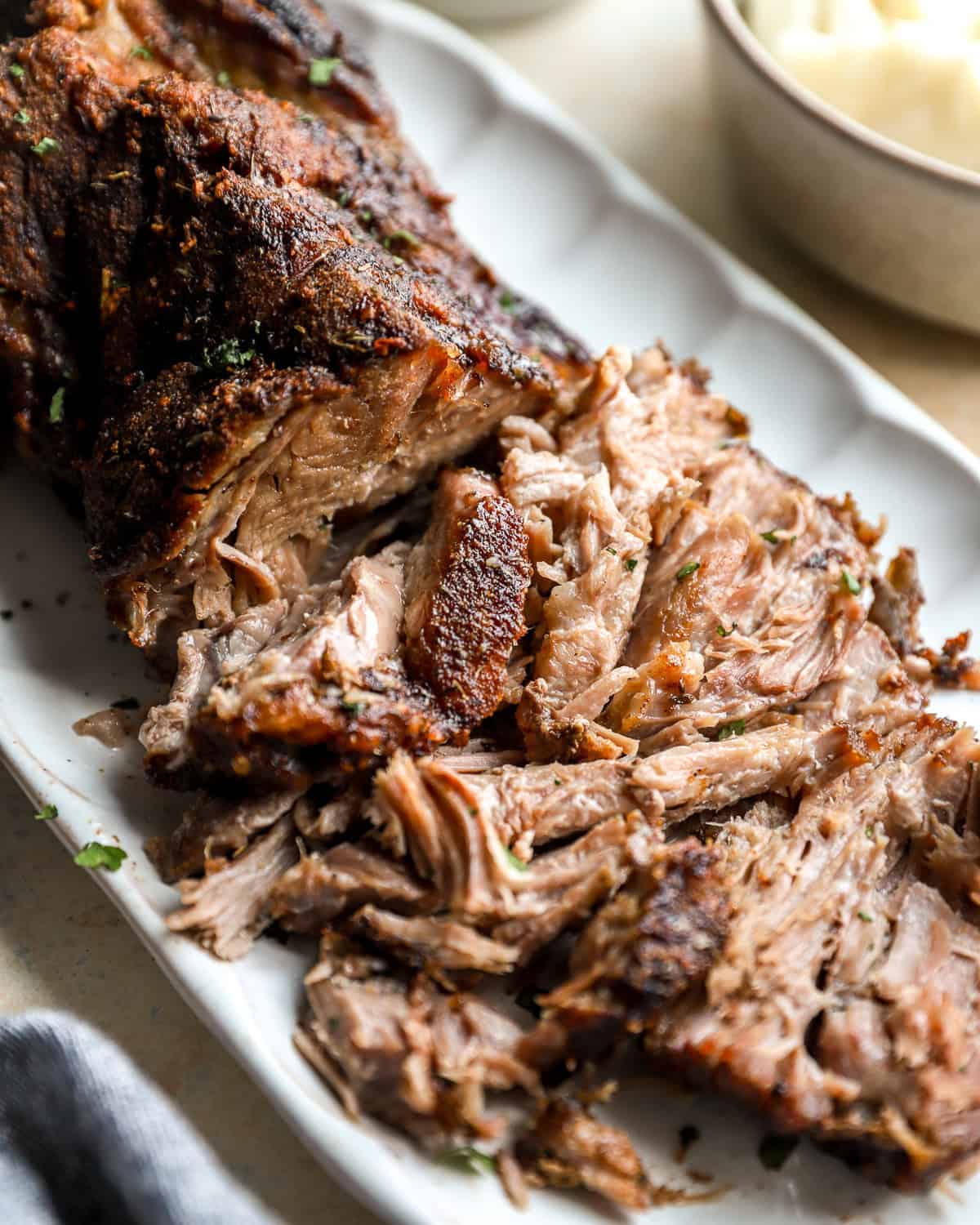 Shredded roasted pork shoulder with crispy browned edges served on a platter.