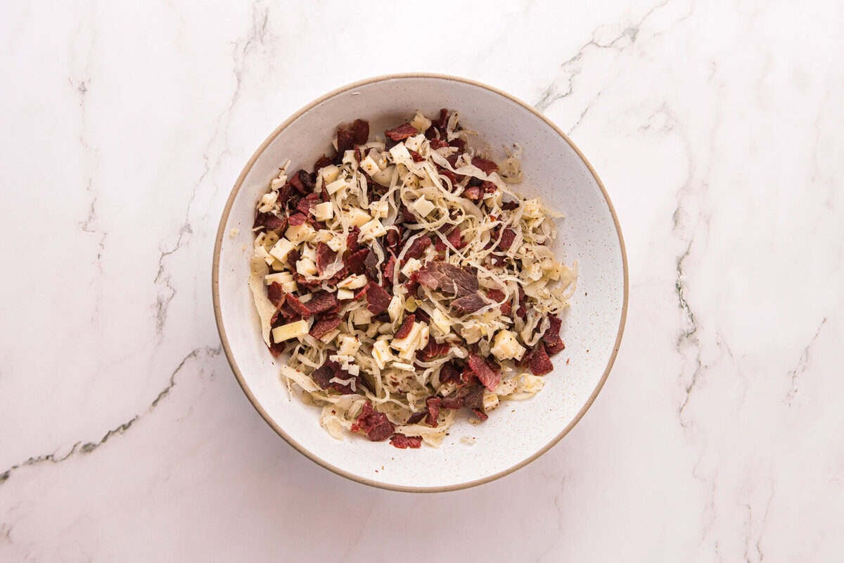 A bowl of crisped corned beef, shredded sauerkraut, and chopped Swiss cheese mixed together for the filling.