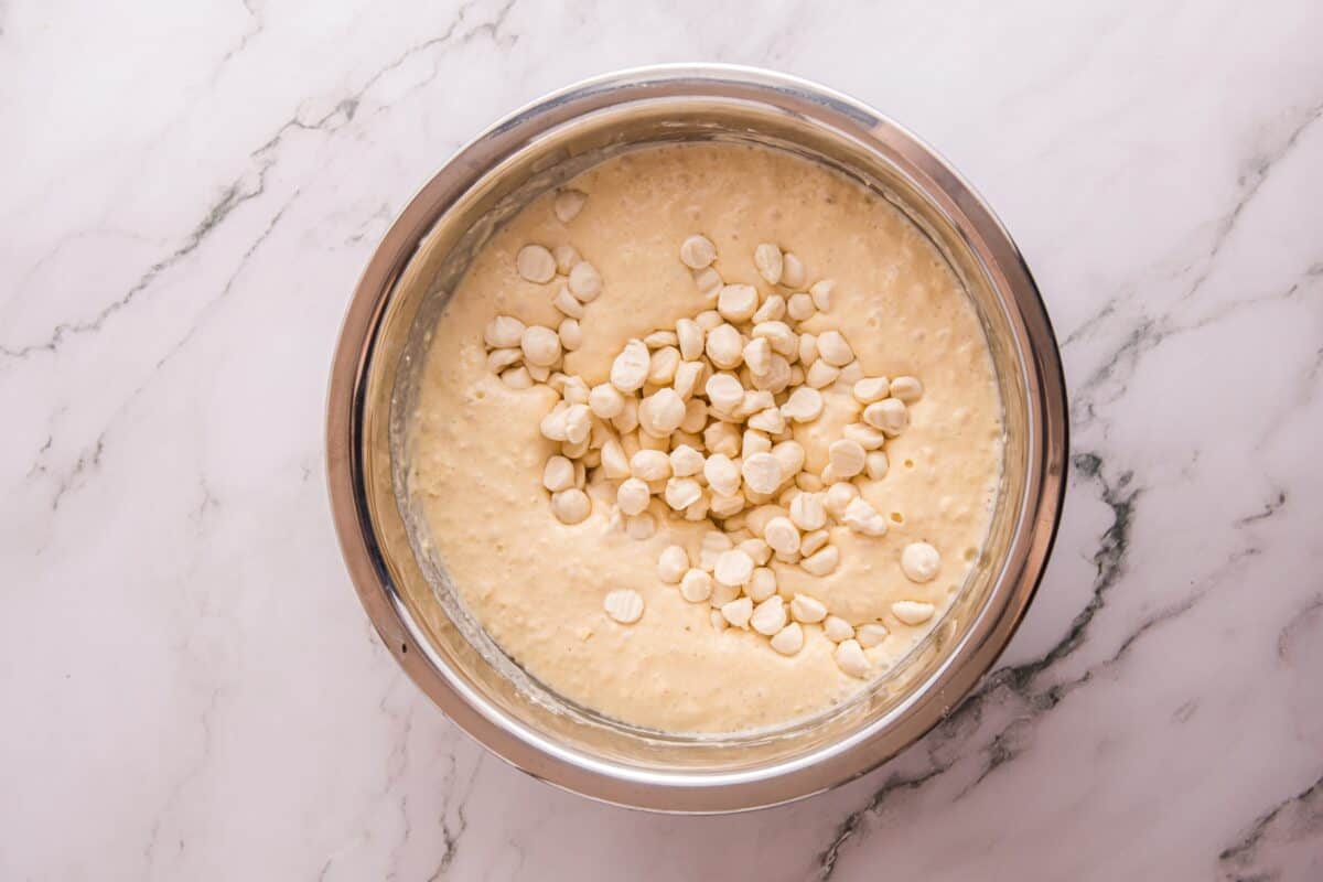 Frozen cheesecake bites folded into pancake batter in a stainless steel bowl