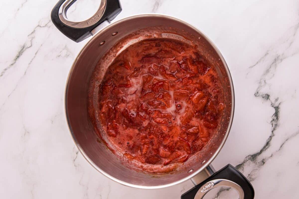 Strawberry sauce simmering and thickening in a saucepan on the stove