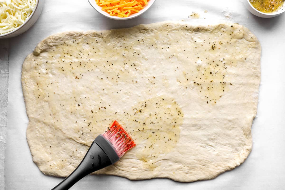 Pizza dough rectangle brushed with garlic herb butter before adding cheese for stuffed cheesy bread