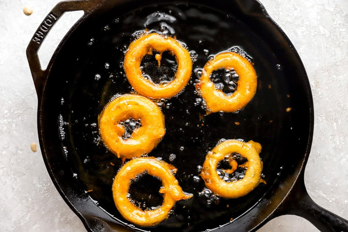 frying pan with oil and onion rings frying