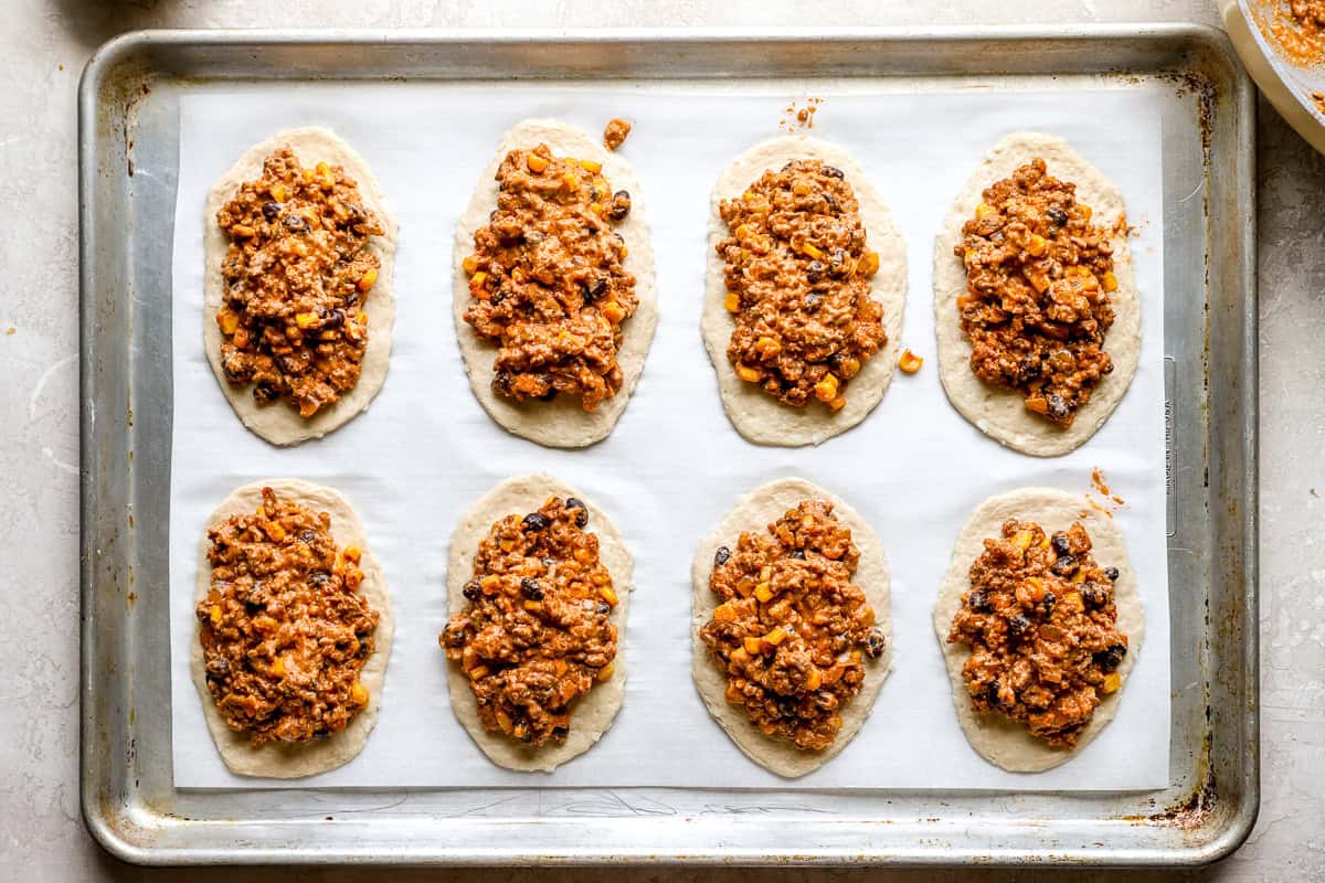 Rolled biscuit dough rectangles topped with taco filling before being sealed into hot pockets.