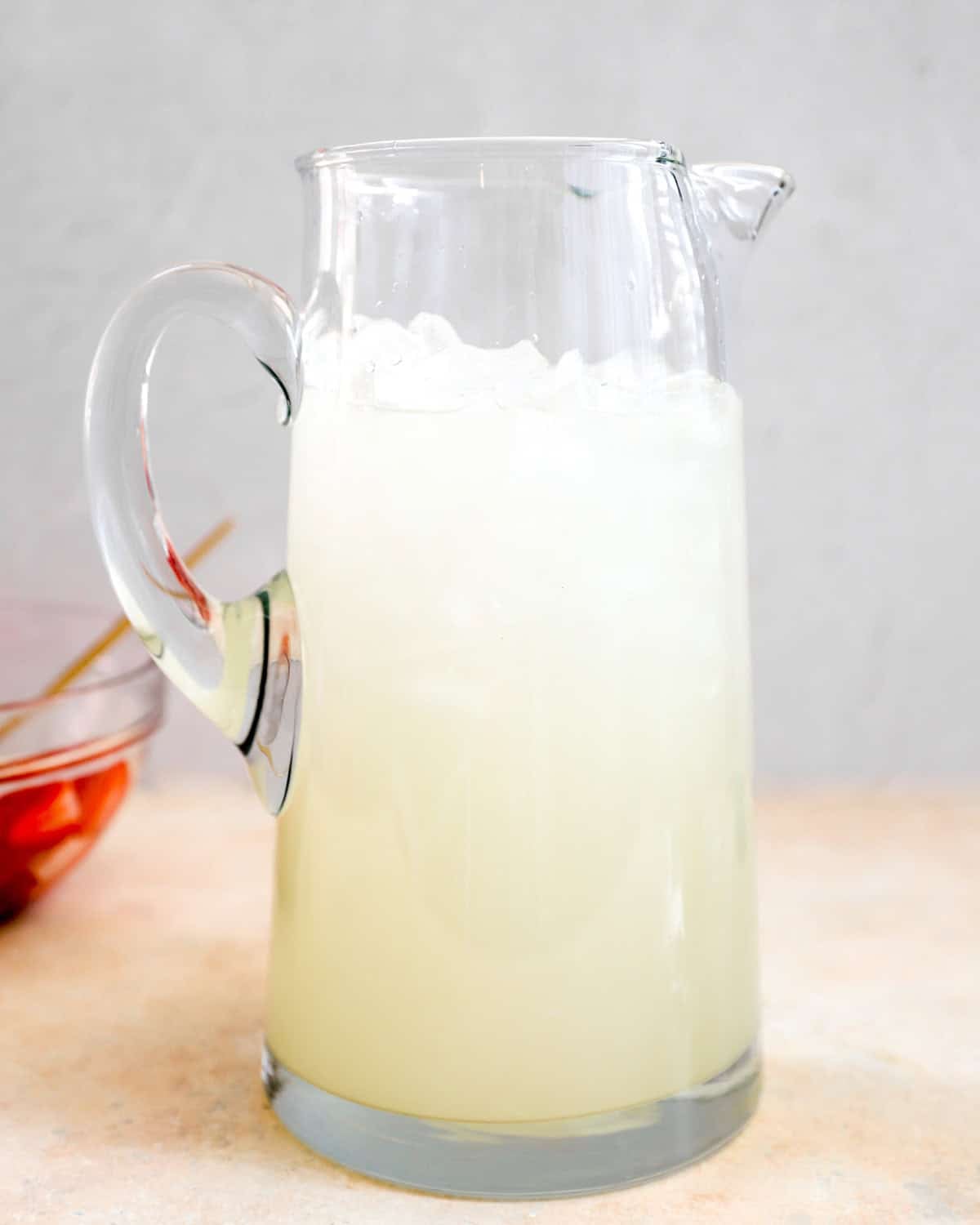 Brocca di vetro riempita con limonata fresca e ghiaccio prima dell'aggiunta delle fragole