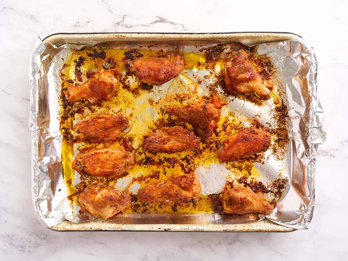 Overhead photo of golden brown baked chicken wings fresh out of the oven on a baking sheet.