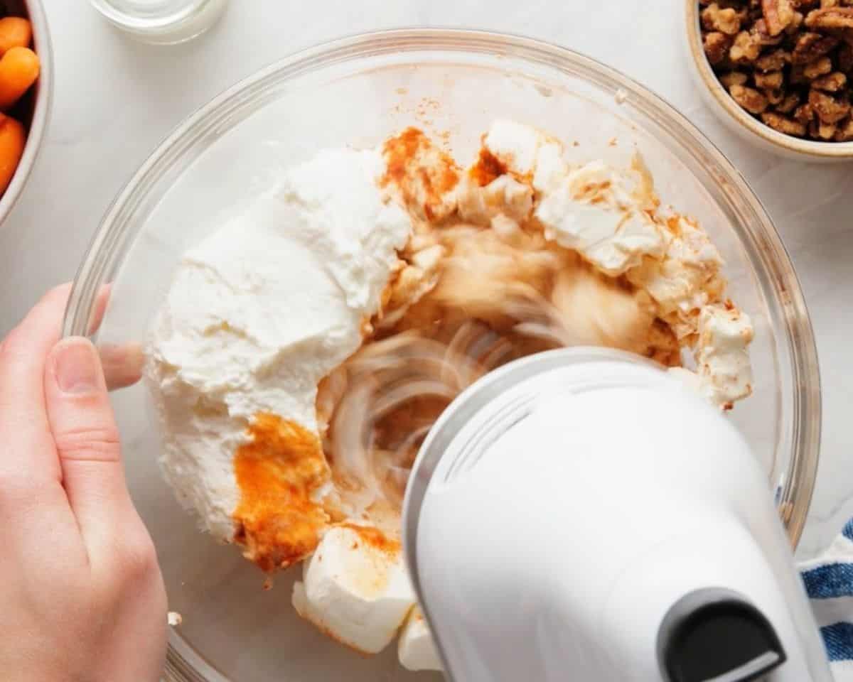 Beating cream cheese, yogurt, pepper, hot sauce, paprika, and lemon juice with a hand mixer.