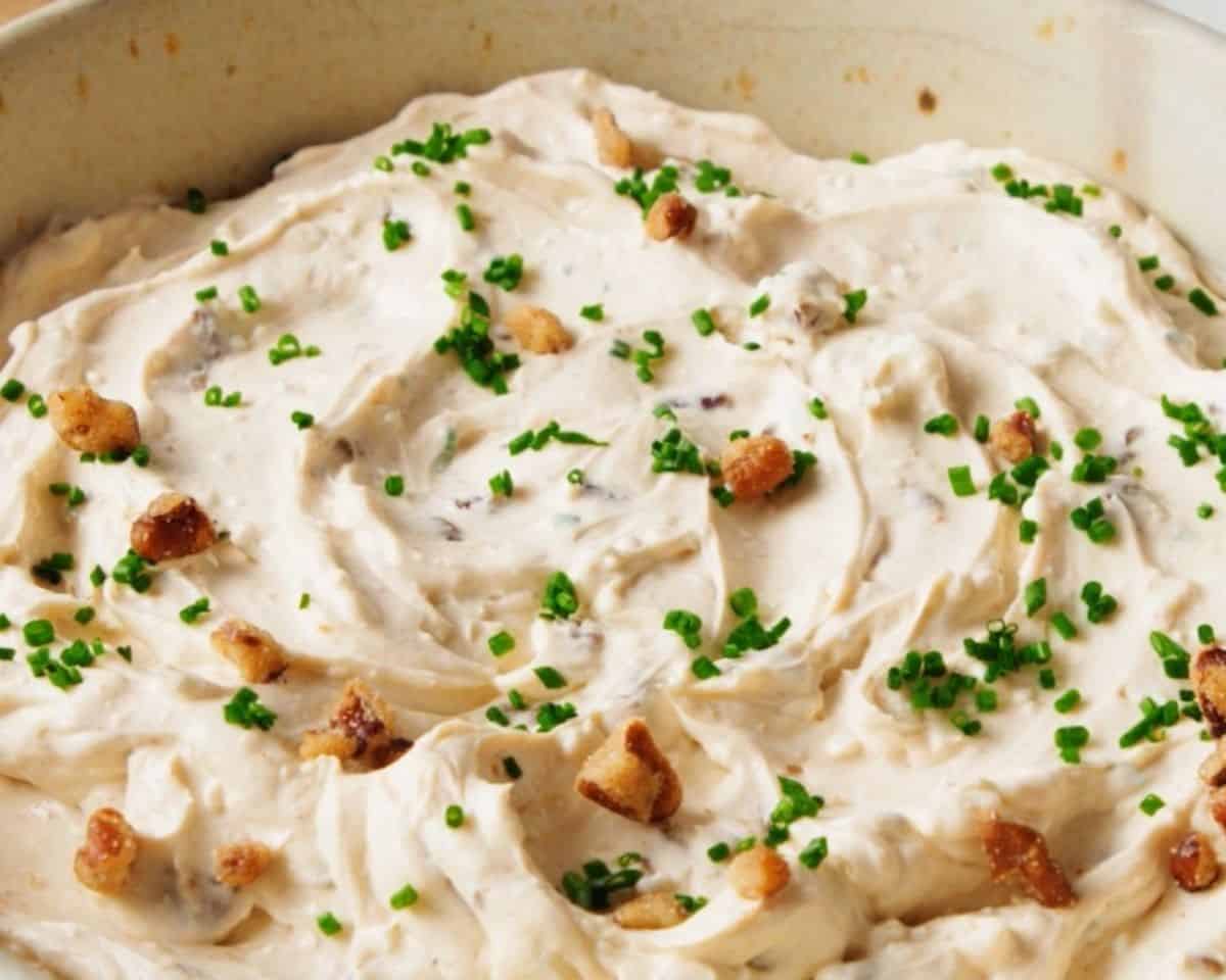 Smoky blue cheese dip in a bowl garnished with chives and pecans.