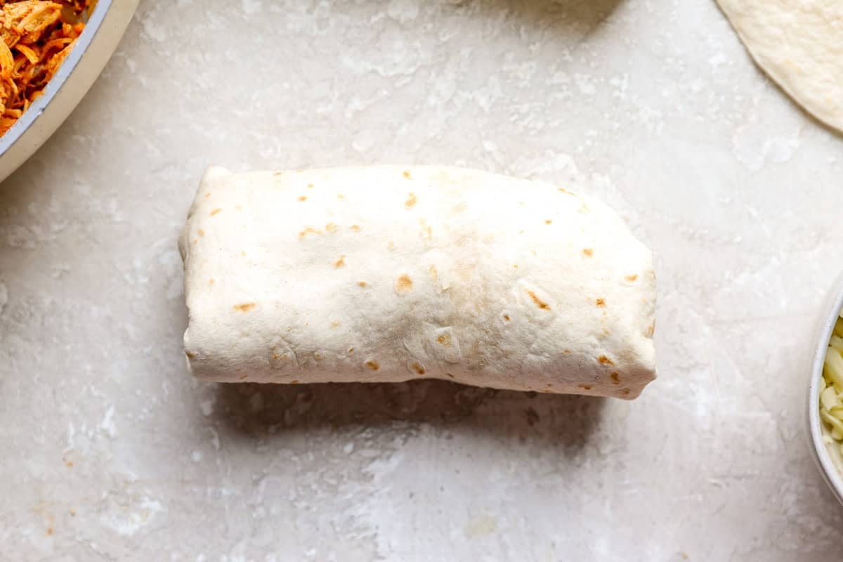 A tightly rolled chimichanga ready to go into the hot oil.