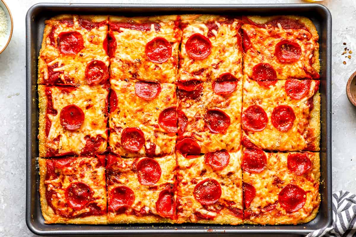 Baked sheet pan pizza sliced into squares, shown from overhead