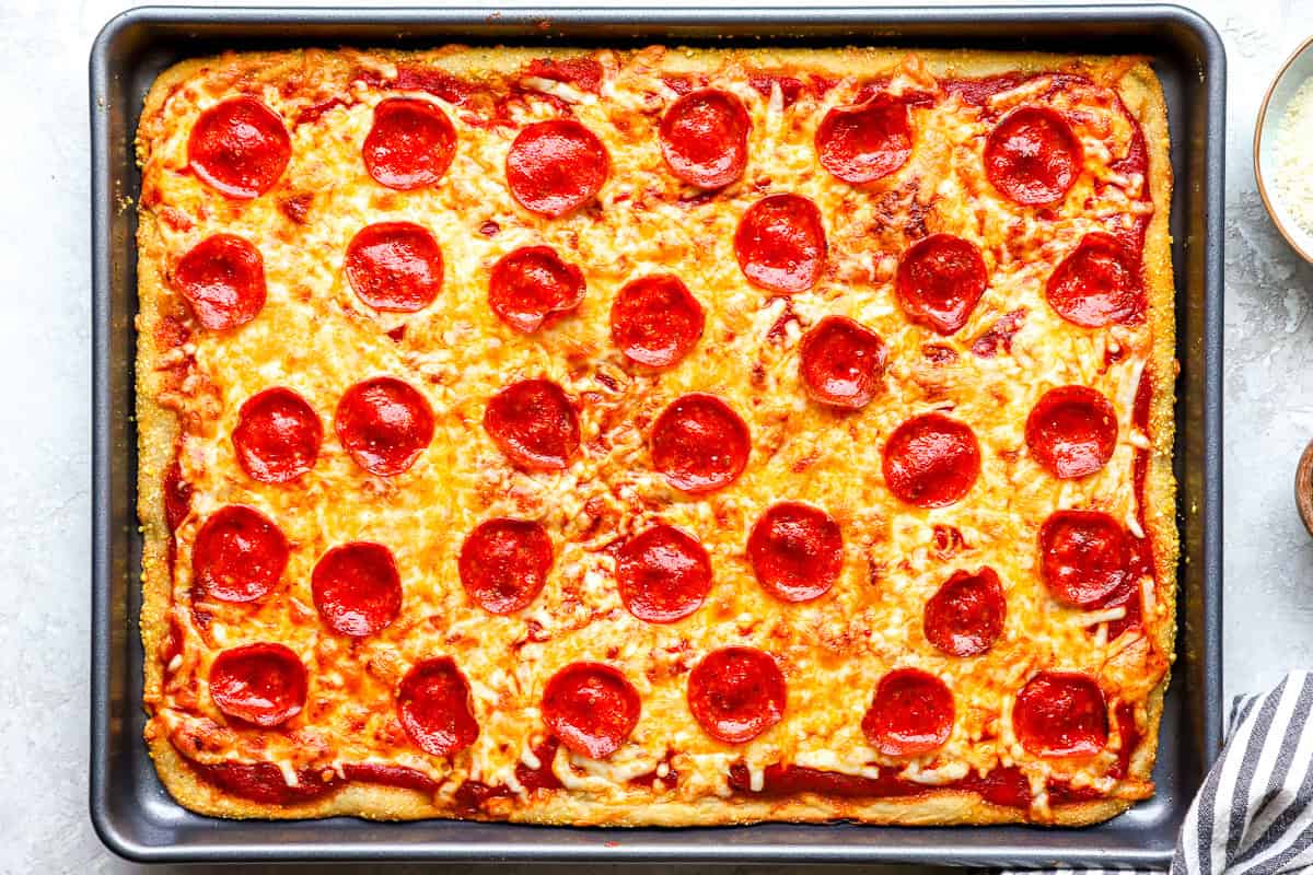 Fully baked sheet pan pizza with golden, bubbly cheese and crispy browned crust