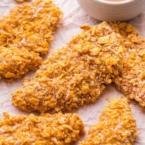 Crispy cornflake buffalo chicken tenders arranged next to a bowl of brown butter buffalo sauce