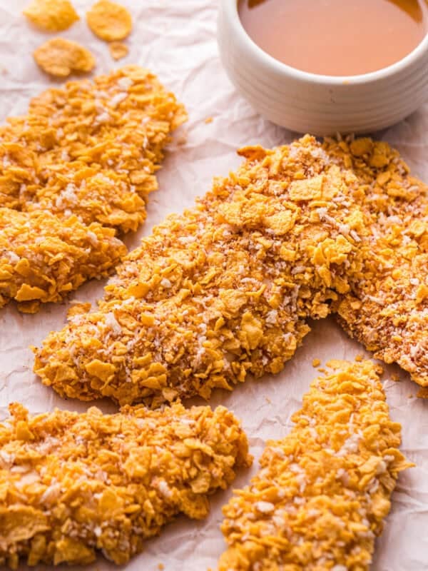 Crispy cornflake buffalo chicken tenders arranged next to a bowl of brown butter buffalo sauce