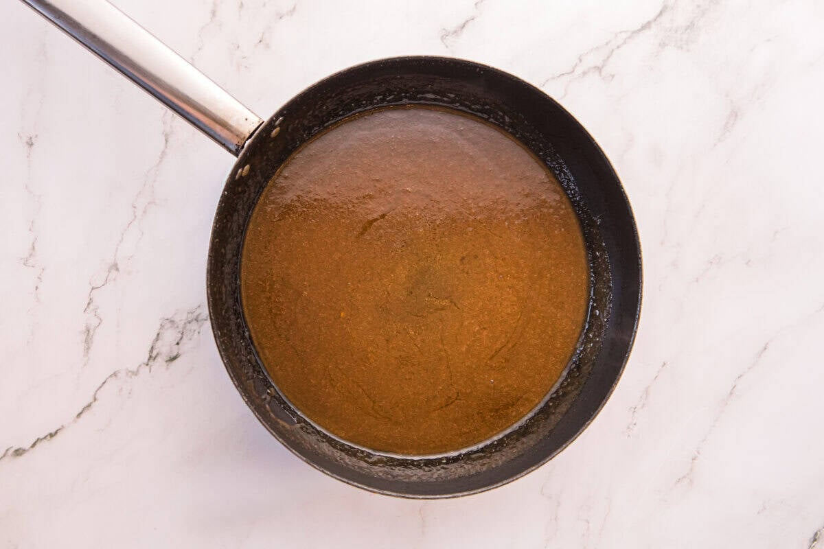 Glossy, deep amber brown butter buffalo sauce in a saucepan