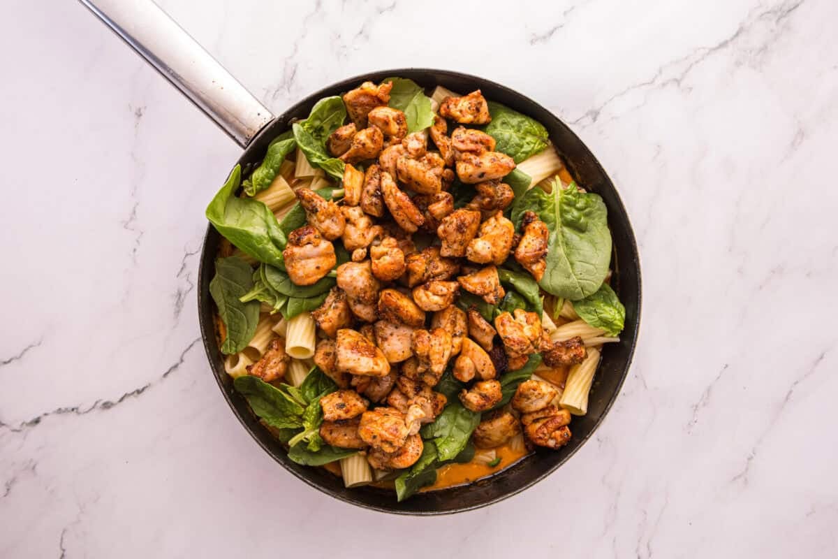 Cooked rigatoni, baby spinach, and seared chicken piled into the skillet before tossing with the sauce.